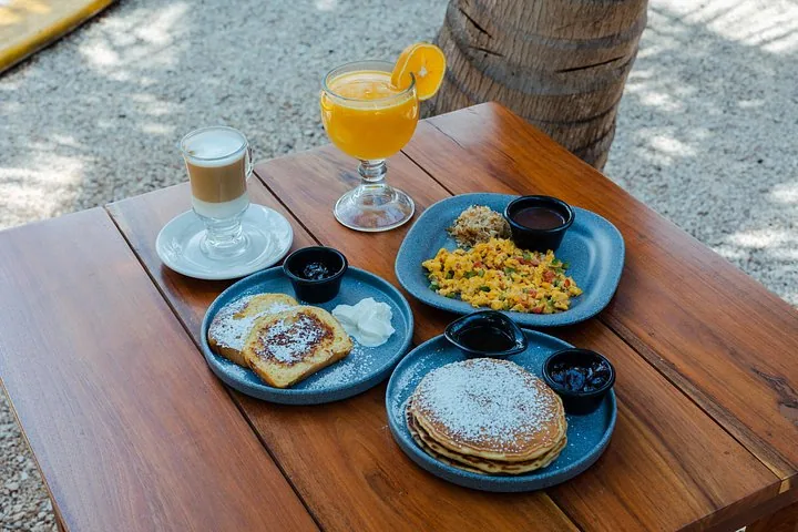 Breakfast table featuring pancakes, French toast, scrambled eggs, and drinks.