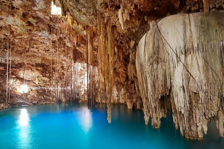 A stunning underground cenote with turquoise water and hanging stalactites.